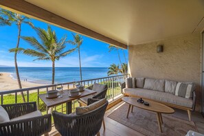 Un balcon avec vue sur la plage et l’océan, aménagé avec un canapé, des chaises et une table.
