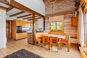 A rustic cabin interior with a wooden dining table, benches, and a kitchen area with wooden cabinets and a refrigerator. - Marcotte - 8 pers - beautiful view (Haute-Nendaz)