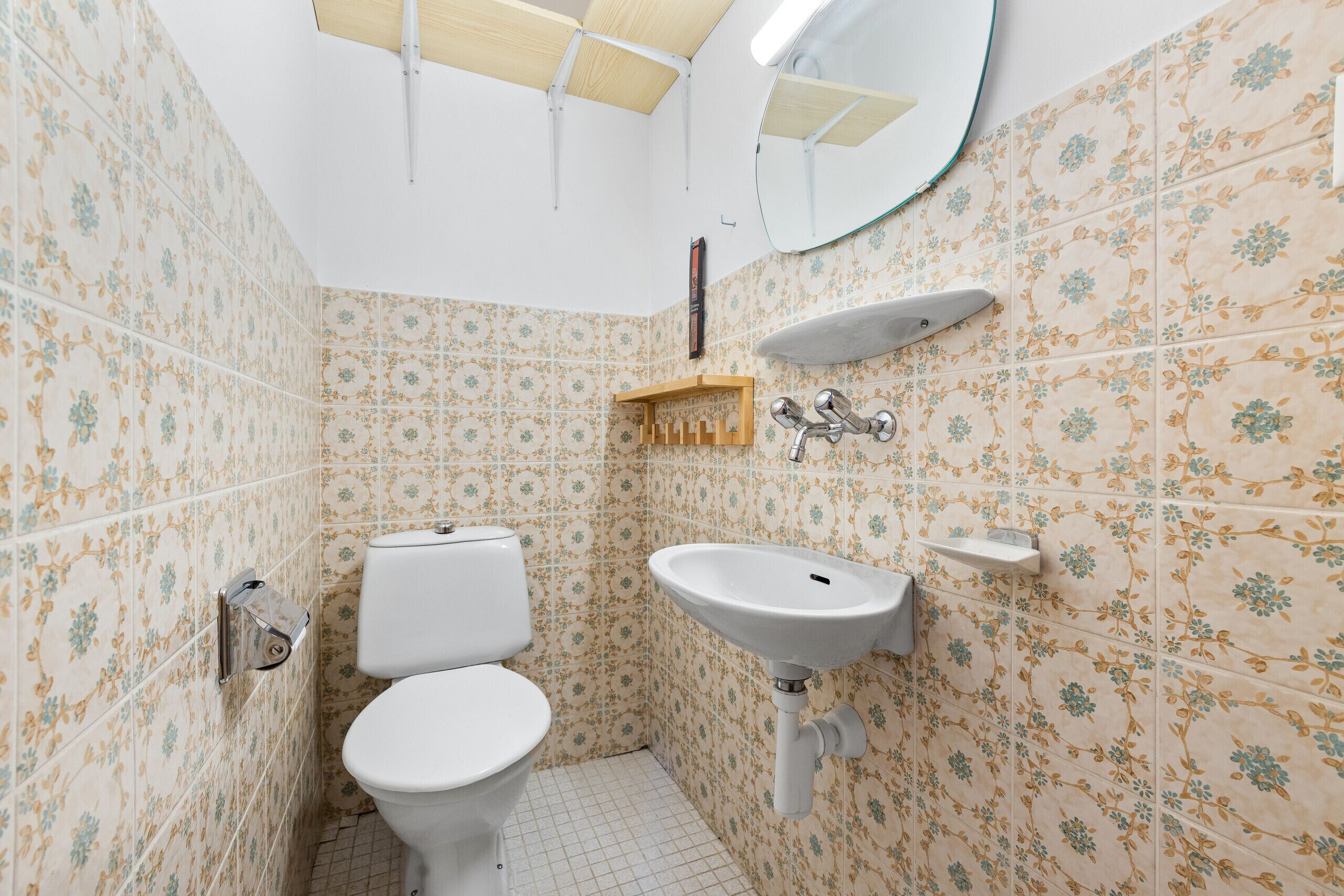 A bathroom with a toilet, sink, and mirror.