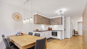 Eine moderne Küche mit Holzschränken, einem Esstisch mit Stühlen und Pendelleuchten.