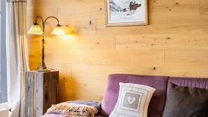 Ein gemütliches Zimmer mit einer Holzwand, einem violetten Sofa, einer Lampe und einem gerahmten Bild.
