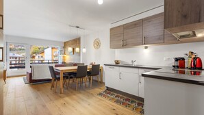 Eine moderne Küche mit Holzausstattung, einem Essbereich mit Tisch und Stühlen und Blick auf umliegende Gebäude.