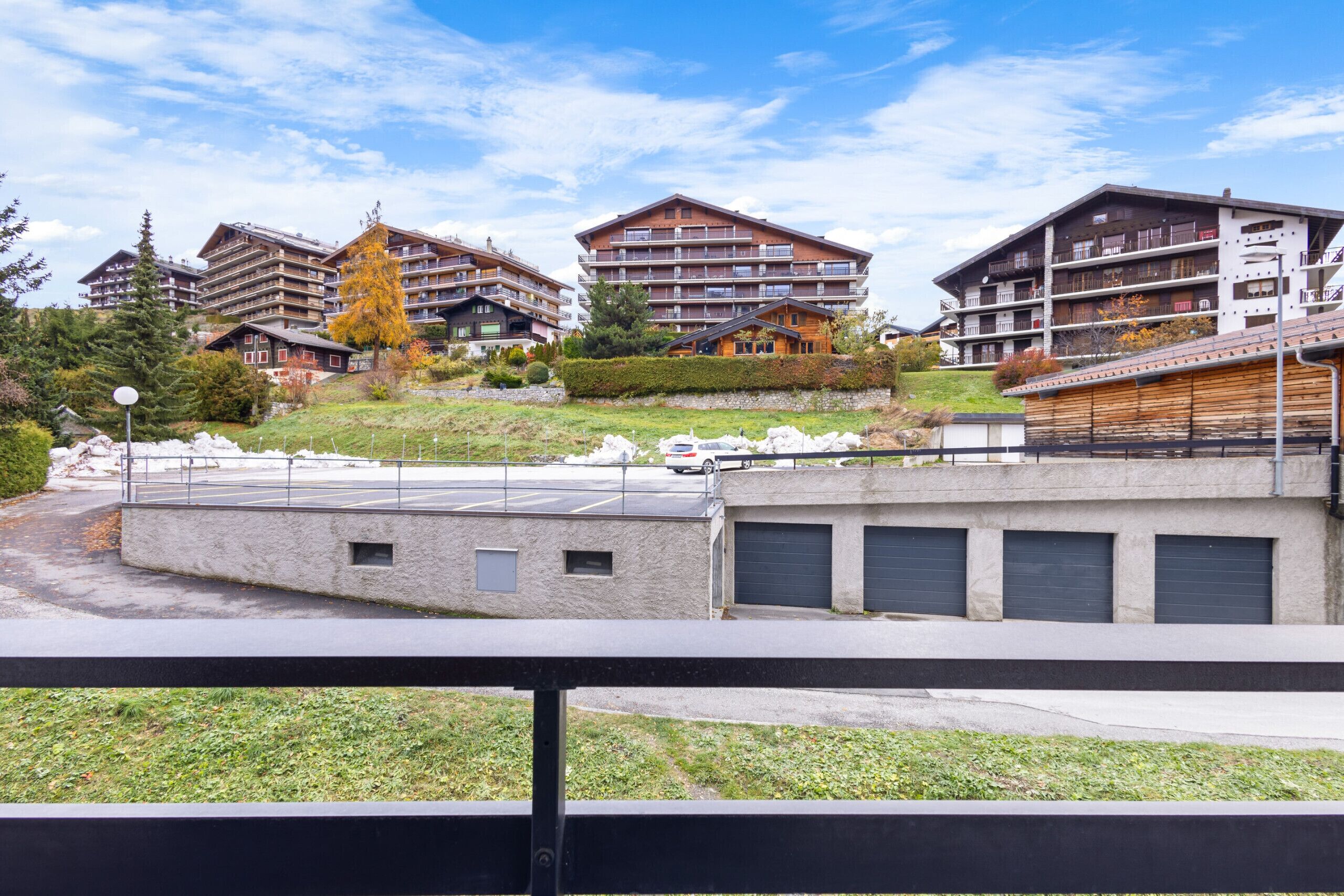 Ein modernes Hotel mit mehreren Etagen, Balkonen und einem Parkplatz.
