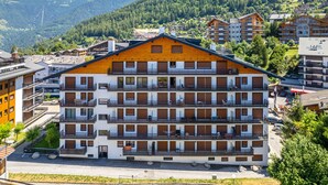 Ein mehrstöckiges Hotel mit Balkonen vor einer gebirgigen Kulisse.
