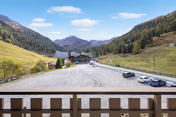 A parking lot with cars, a building with a sloped roof, and mountains in the background. - Dents-Rousses D2 - 4 people - Siviez (Siviez)