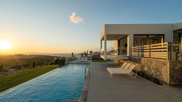 Ein modernes Haus mit Swimmingpool, Liegestühlen und Blick auf die Landschaft.
