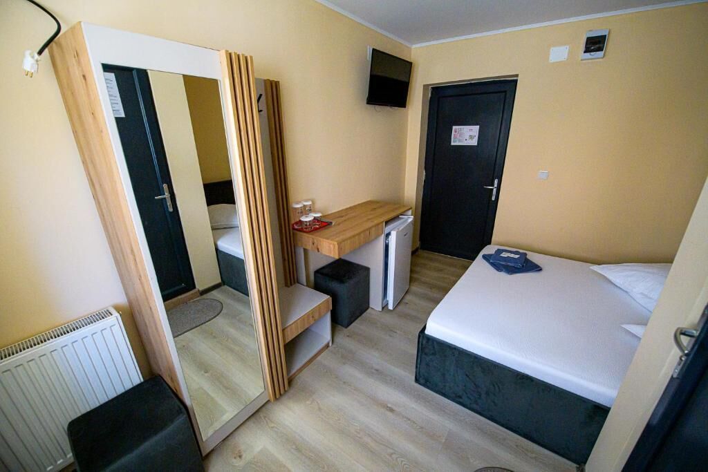 Una stanza piccola con un letto, una scrivania, uno specchio e un armadio.