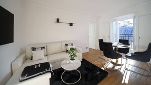 Un salon moderne avec un canapé blanc, une table basse ronde et des chaises noires.