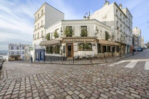Un edificio histórico con una cafetería en la planta baja, que ofrece mesas al aire libre y vistas a la calle.