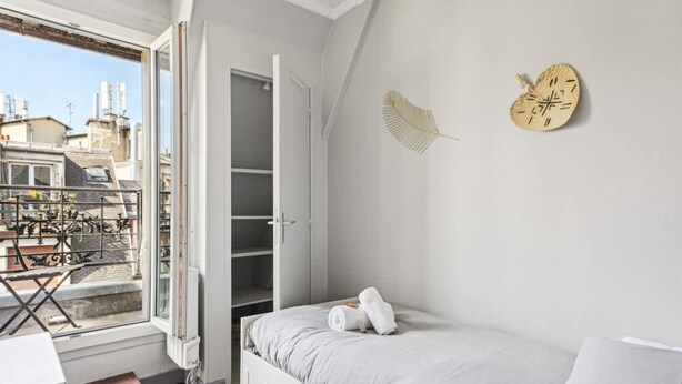 Une chambre à coucher avec un lit, une fenêtre, un balcon et une armoire.