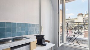 Una cucina compatta con piano cottura integrato, macchina da caffè e finestra vista balcone con mobili da esterno.