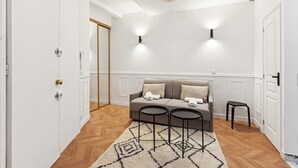 A modern living room with a sofa, two small tables, and a patterned rug. - Charming Studio - Pereire - Lease Mobility (Paris)