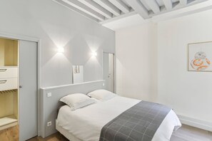 Une chambre à coucher comprenant un lit, une armoire, un miroir et une œuvre d’art accrochée au mur.