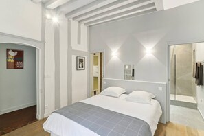 A bedroom with a bed, a shower area, and a door leading to another room. - Exceptional Appt - Saint-germain- Mobility Lease (Paris)