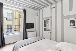 A bedroom with a bed, a dresser, a mirror, and a window with curtains. - Exceptional Appt - Saint-germain- Mobility Lease (Paris)