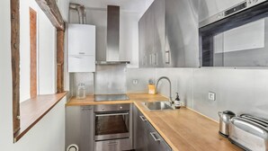 A modern kitchen with stainless steel appliances, wooden countertops, and a built-in oven. - Exceptional Appt - Saint-germain- Mobility Lease (Paris)