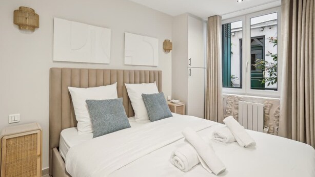 Ett modernt hotellrum med en stor säng, ett nattduksbord, ett element och ett fönster med gardiner.