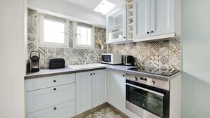 A modern kitchen with white cabinets, a microwave, a coffee maker, and patterned tile backsplash. - Authentic Apartment - 1BR 6P - Centre de Paris (Paris)