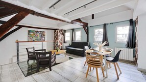 A spacious living area with a dining table, chairs, a sofa, and a large window with curtains. - Authentic Apartment - 1BR 6P - Centre de Paris (Paris)