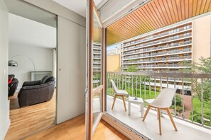 Een modern appartement met balkon, een bank en twee stoelen.