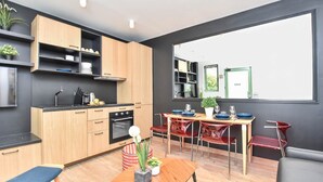 Une cuisine moderne avec des meubles en bois, un coin repas avec des chaises rouges et une grande fenêtre.