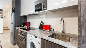 Een moderne keuken met een ingebouwde wasmachine, een magnetron en een RVS-spoelbak.