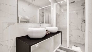 Ein modernes Badezimmer mit zwei großen weißen Waschbecken, einer schwarzen Ablagefläche und einer Duschkabine aus Glas.