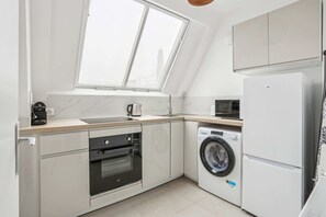 A modern kitchen with a skylight, built-in oven, washing machine, and refrigerator. - Charmant Appt Avec Balcon - Ternes- Bail Mobilit (Paris)