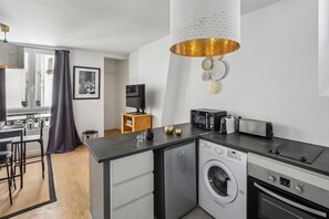 Une cuisine compacte équipée d’un lave-linge, d’un four à micro-ondes, d’un grille-pain et d’un évier.