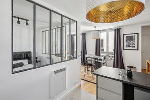 A modern interior with a large mirror, a dining area, and a kitchen. - Studio at the Heart of the Marais Rue des Rosiers (Paris)
