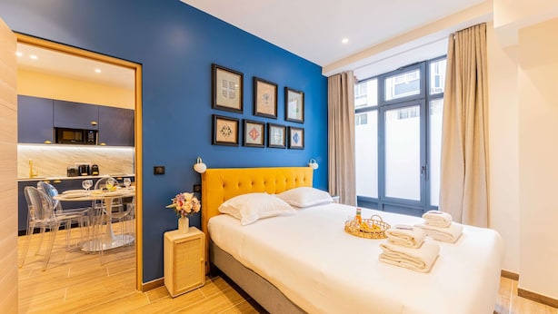 A hotel room with a bed, a dining area, and a large window. - Amazing Apartment - 2BR 6P - Gare du Nord (Paris)