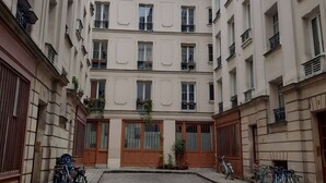 A courtyard with a central open space surrounded by multi-story buildings with balconies and windows. - A Cozy Refuge - 18th - Mobility Lease (Paris)