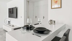 A modern dining area with a white island, black plates, wine glasses, and a framed picture on the wall. - Charmant Appt 1brd 2P - Neuilly-sur-seine (Neuilly-sur-Seine)