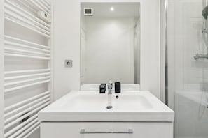 A modern bathroom with a white sink, a mirror, and a shower area. - Charmant Appt 1brd 2P - Neuilly-sur-seine (Neuilly-sur-Seine)