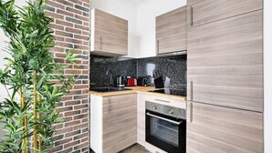 Een moderne keuken met lichte houten kastjes, een zwart aanrecht en een bakstenen muur.