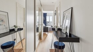 A modern, well-lit hallway with a dining area, a kitchen, and a living space visible through an open door. - Extra Studio on the 23rd Floor - Stunning View (Paris)