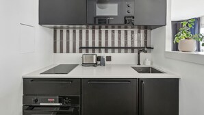 A modern kitchen with a microwave, toaster, and built-in oven. - Extra Studio on the 23rd Floor - Stunning View (Paris)