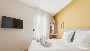 A hotel room with a bed, a flat-screen TV mounted on the wall, a bedside table, and a mirror. - Maison Atypique de 82 m (Vincennes)
