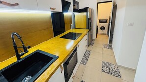 A modern kitchen with a yellow countertop, black sink, and stainless steel appliances. - Superb 6-person 80m2 apartment in Agde (Agde)