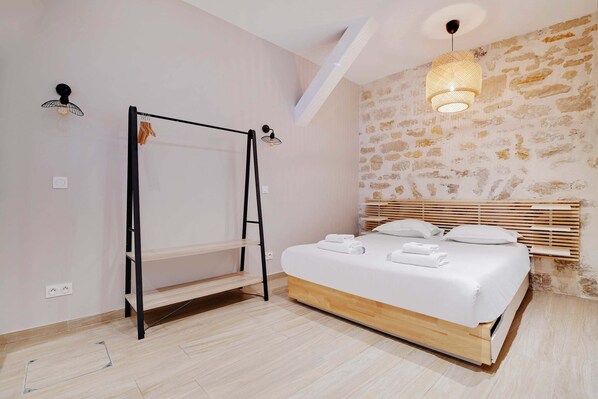 Un dormitorio con literas, cabecera de madera, pared de piedra y lámpara colgante.