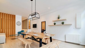 Un comedor moderno con una mesa de madera, bancos y una lámpara colgante.