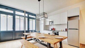 Una cocina moderna con una mesa de comedor de madera, bancos y una lámpara colgante.