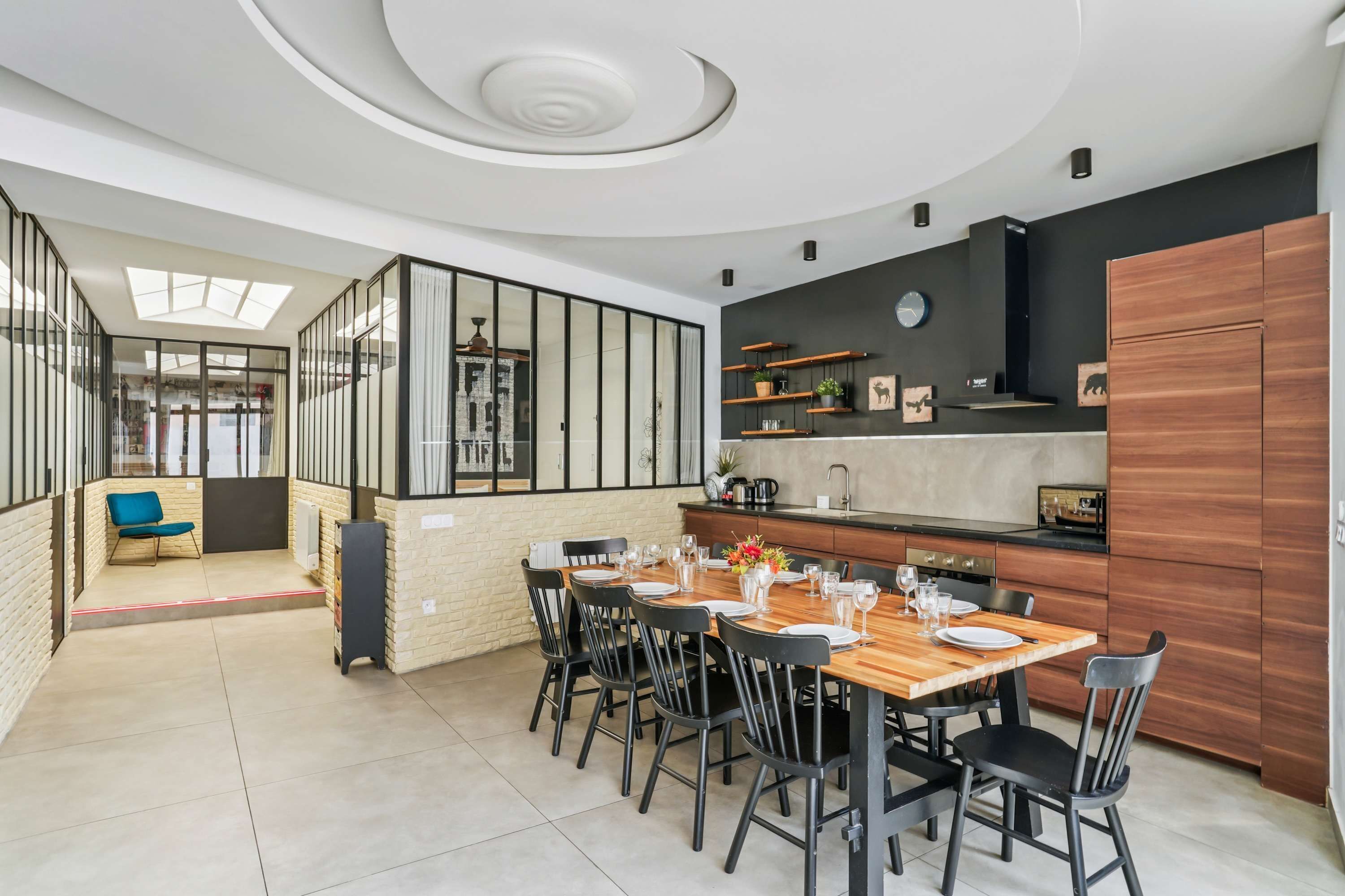 Une cuisine moderne avec un coin repas, comprenant une table en bois, des chaises noires et un four encastré.