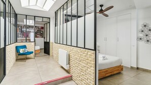 Egy modern hálószoba, melyben tetőablak, mennyezeti ventilátor, ágy és gardróbszekrény található.