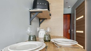 Un coin repas avec une table en bois dressée pour deux personnes, une machine à café noire et une bouilloire blanche.