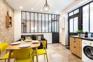 A modern kitchen with a dining area, a washing machine, and a large window. - Amazing Apartment - 1BR 4P - Bastille (Paris)