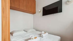 Une chambre d’hôtel avec un lit, deux serviettes blanches, une télévision et un lambris en bois.