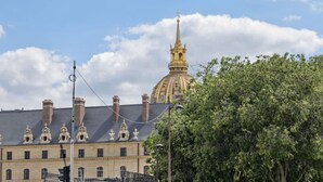 Un bâtiment historique doté d’un dôme imposant et d’une haute flèche, entouré d’une végétation luxuriante.