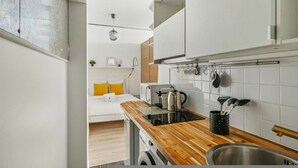 Une cuisine compacte dotée d’un plan de travail en bois, de meubles blancs et d’un four encastré.
