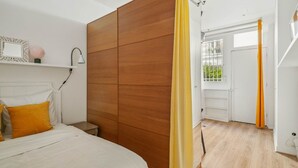 Une chambre à coucher avec un lit, une armoire en bois, une table de chevet et une fenêtre avec des rideaux.